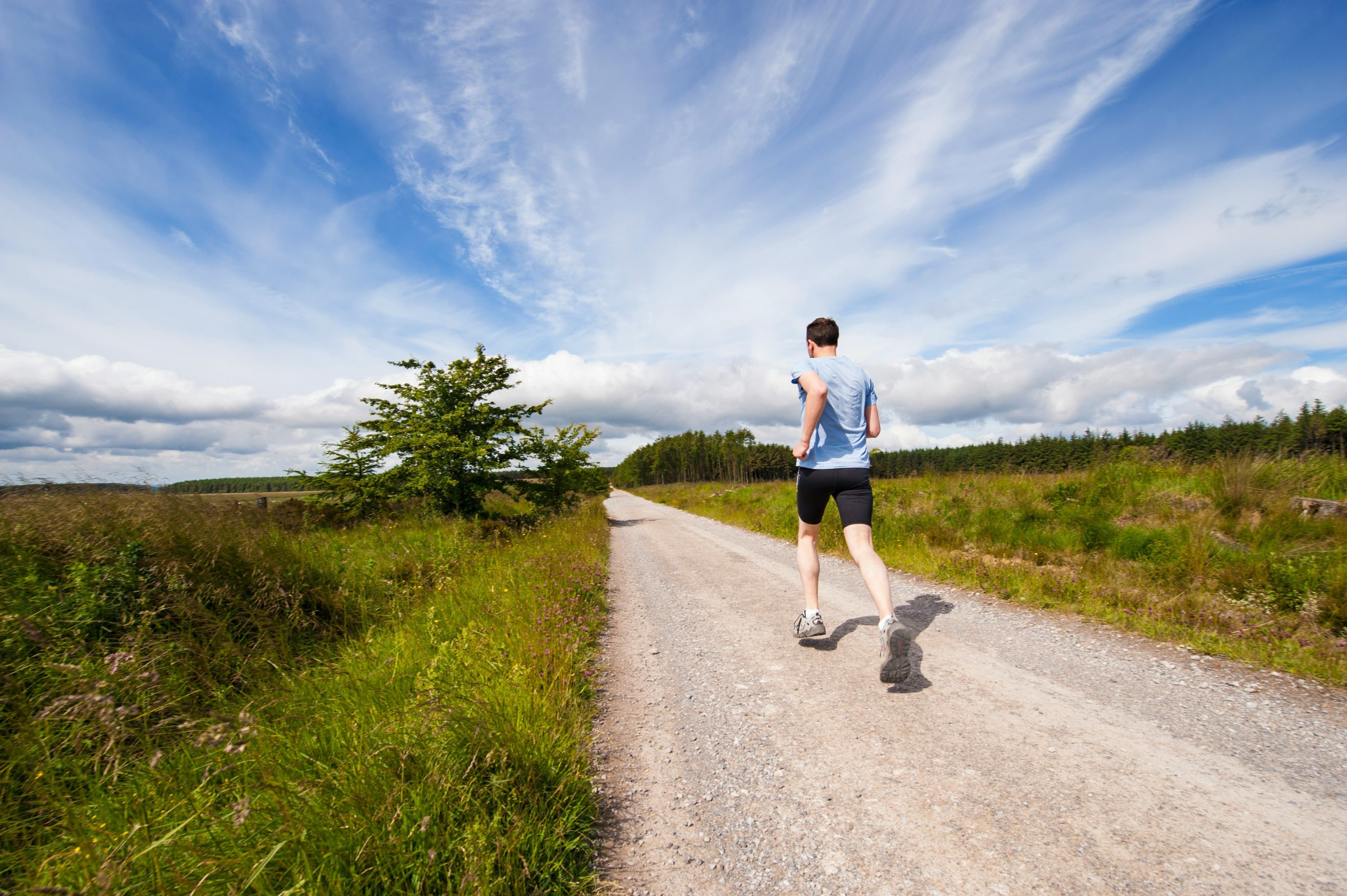 Runner on a rural gravel road under a blue sky